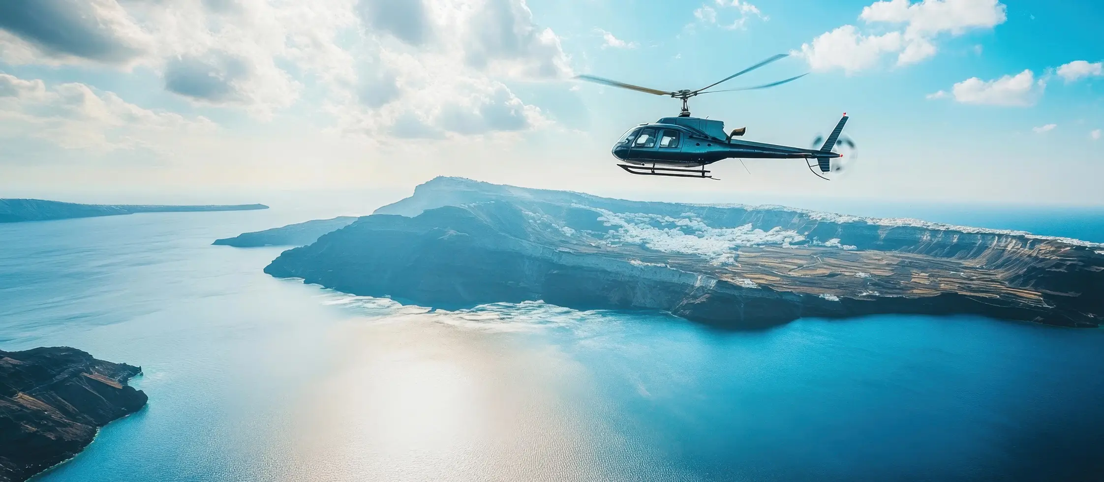 Other Service 1 Helicopter flying over a remote island coastline with bright blue water and dramatic cliffs under a clear sky.