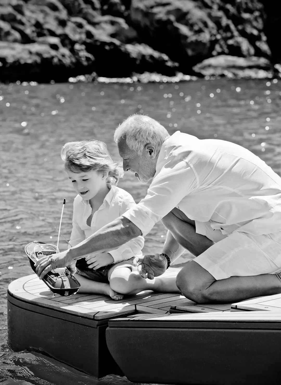 Ownership structuring 2 Grandfather and young boy playing with a model boat on the deck of a luxury yacht, enjoying quiet family time on the water.